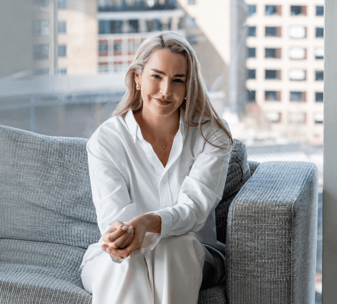 Dr Holly Milmine, founder of Hive Wellness, seated by a window in a bright city office.